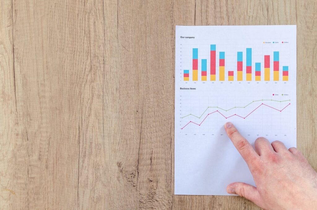 pexels photo 590041 Hand analyzing business graphs on a wooden desk, focusing on data results and growth analysis.